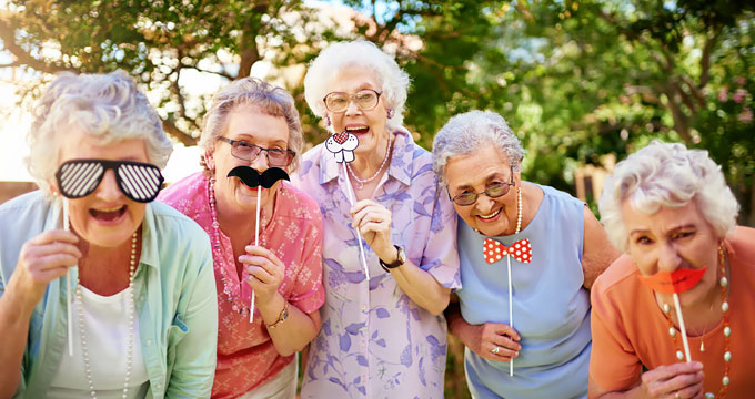 Group of elderly ladies launghing and posing with various face masks