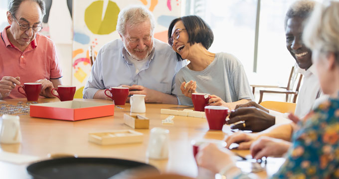 Group of elderly men and women playing games at table and laughing