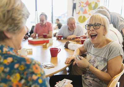 Group of retirees sitting at table playing cards and laughing