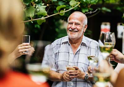 Group of friends holiding wine glasses toasting older gentleman