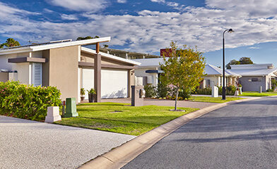 Single storey houses on street with clouds in background