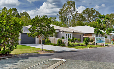 Street with single storey houses in front of trees